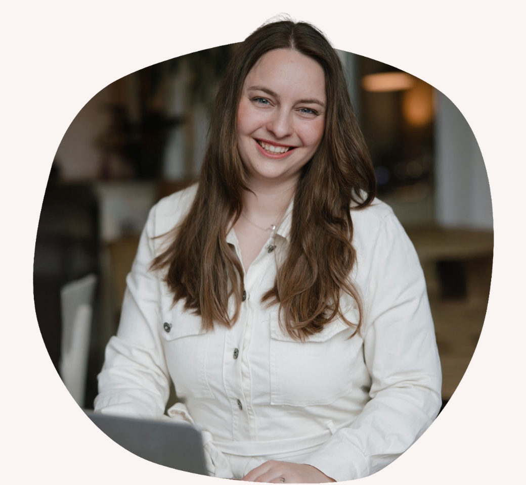 Nathalie Malke sitzt vor ihrem Laptop und laechelt in die Kamera